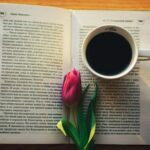 a cup of coffee and a flower on a book